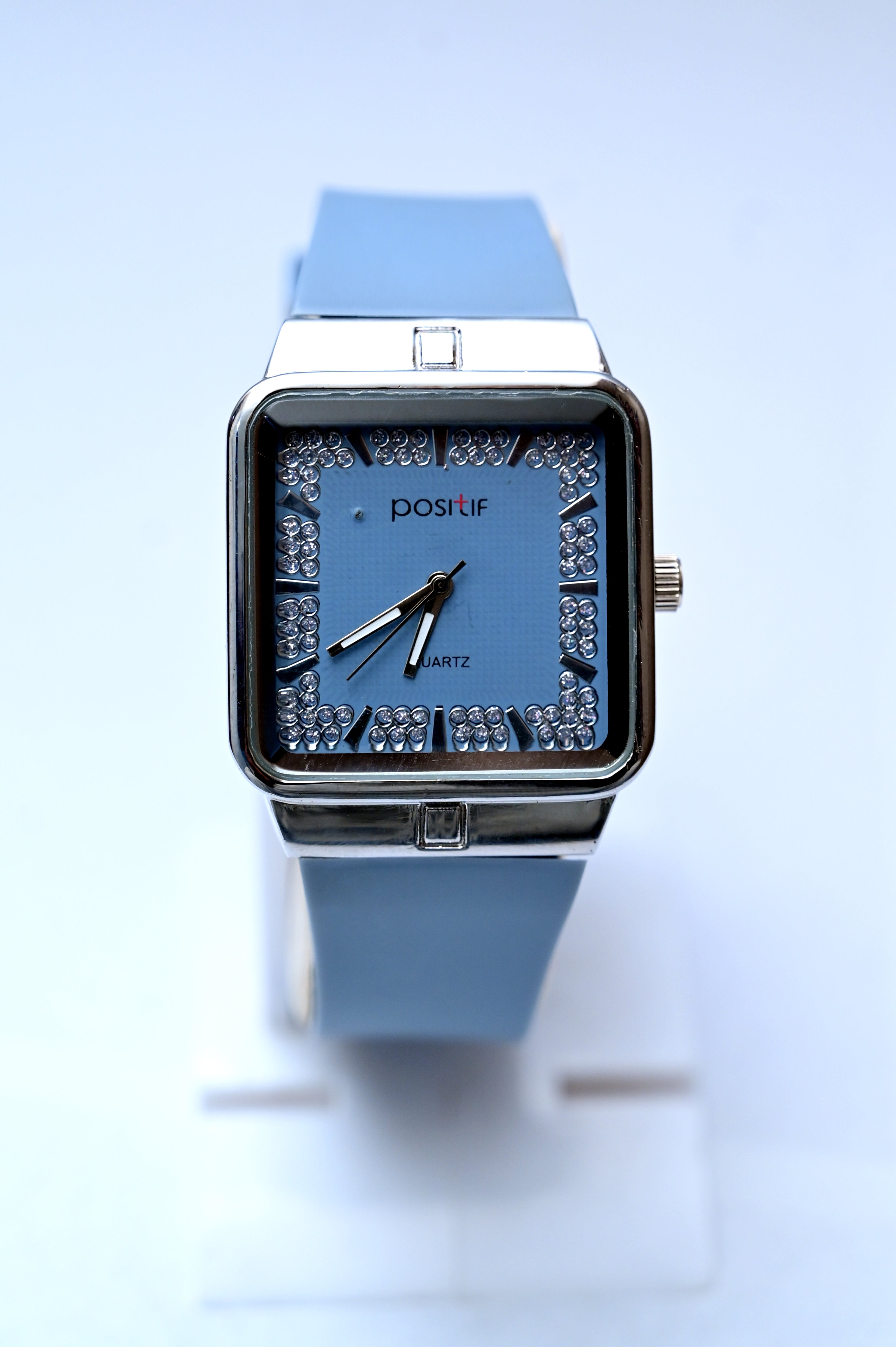 Blue wristwatch with a decorative face on a light blue background