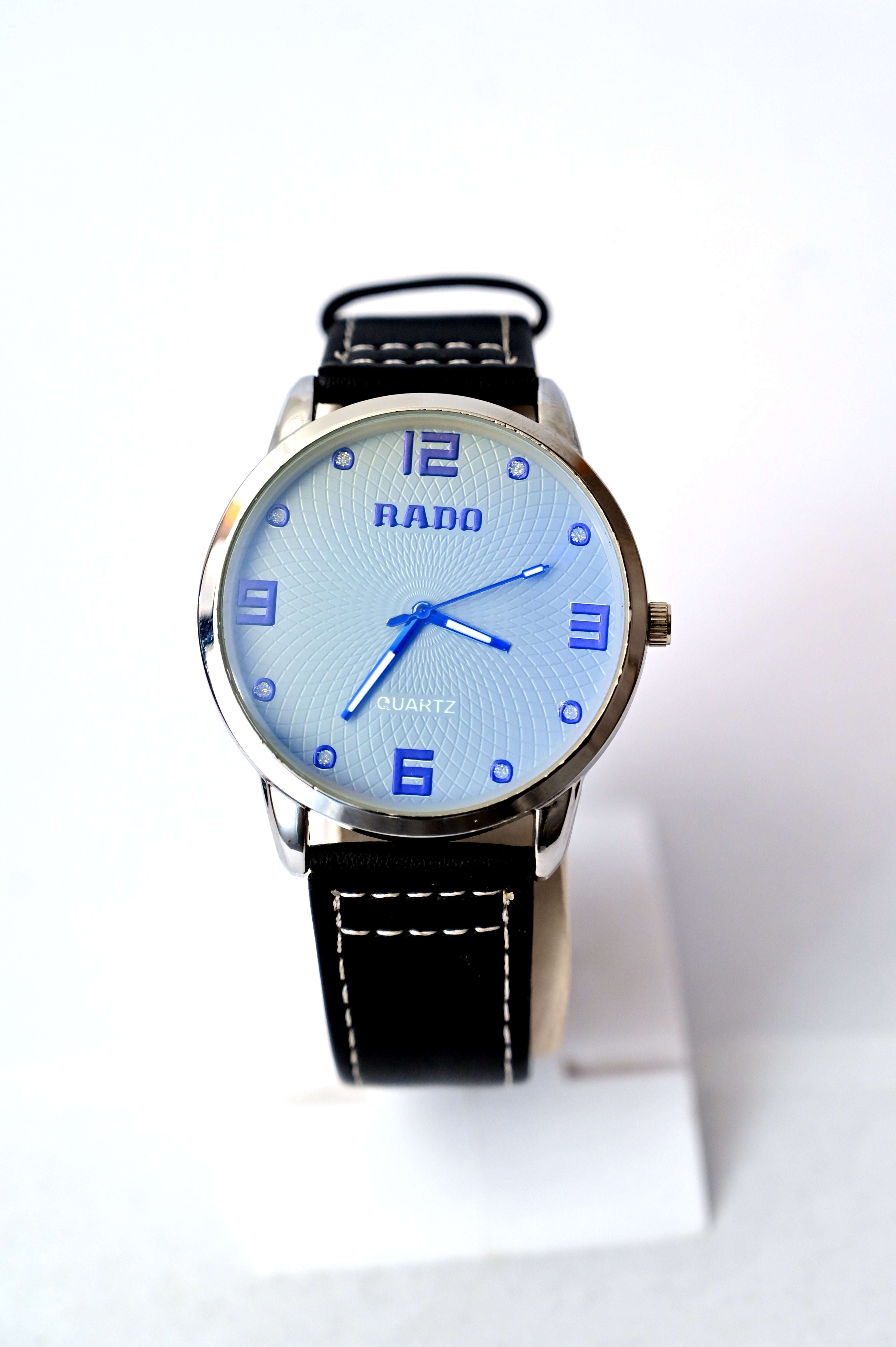 Rado watch with black leather strap and blue dial on a white background