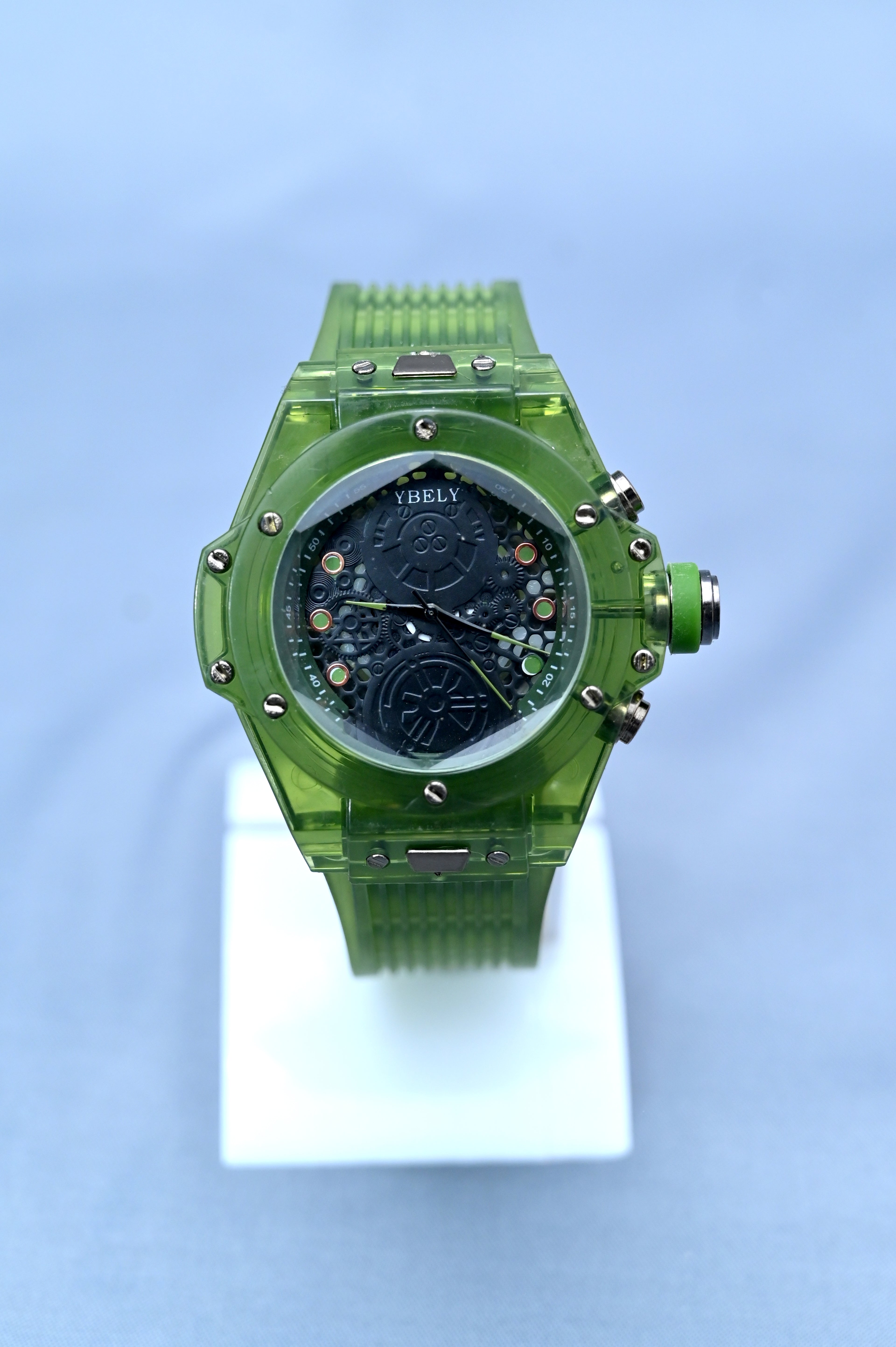 Green watch on a white stand with a light blue background